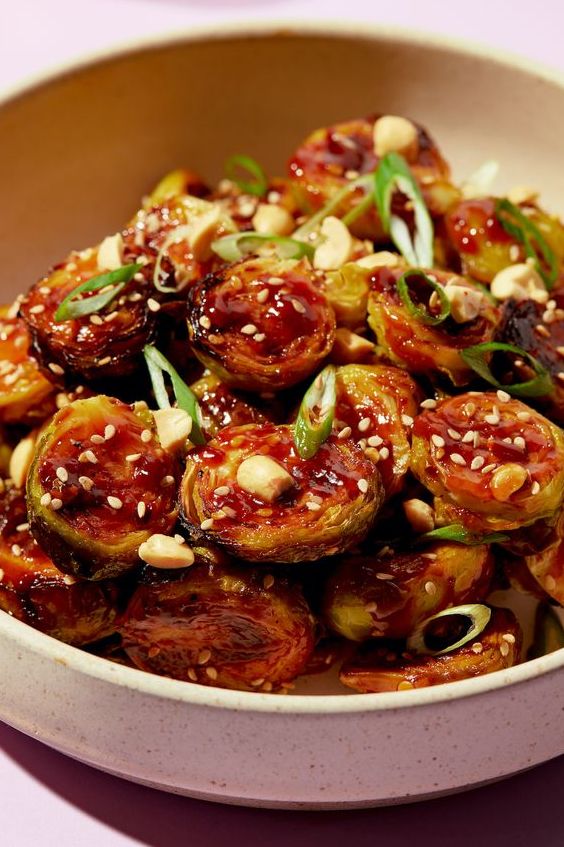 kung pao brussels topped with sesame seeds, peanuts, and scallions