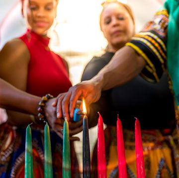 kwanzaa celebration, african american family lighting the kinara candle together at home in spirit of unity