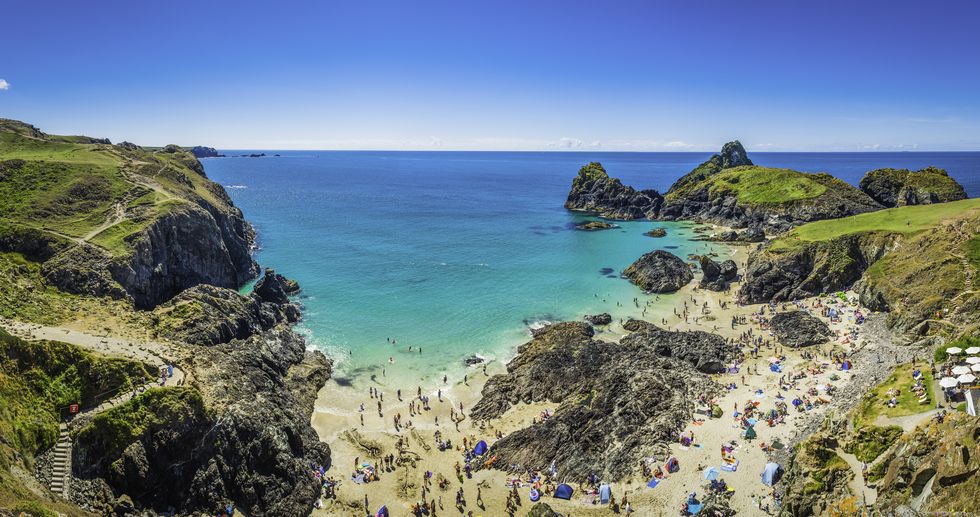 Cornwall crowds of tourists enjoying holiday sunshine Kynance Cove panorama