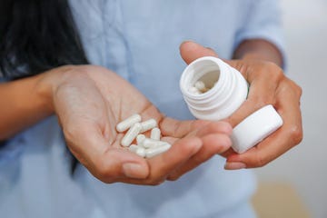 woman holding a pill bottle and white pills in her hands