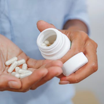 best time to take L theanine woman holding a pill bottle and white pills in her hands