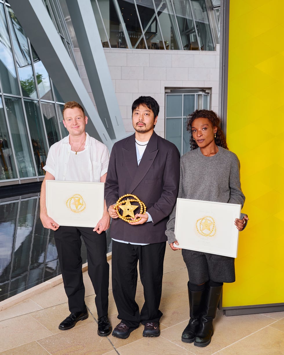 three individuals holding awards inside a modern architectural space