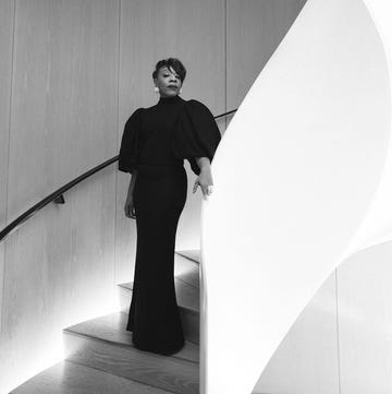 individual in a stylish black gown ascending a modern staircase individual in a stylish black gown ascending a modern staircase