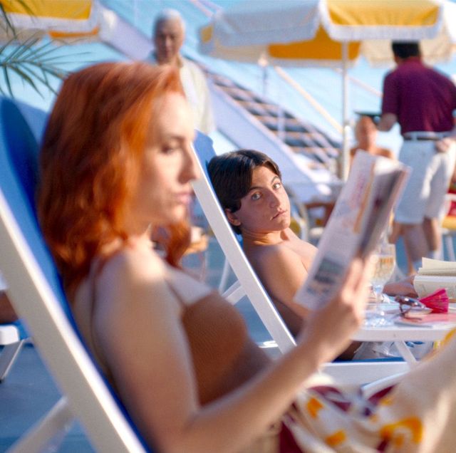 a woman reading a newspaper on a beach