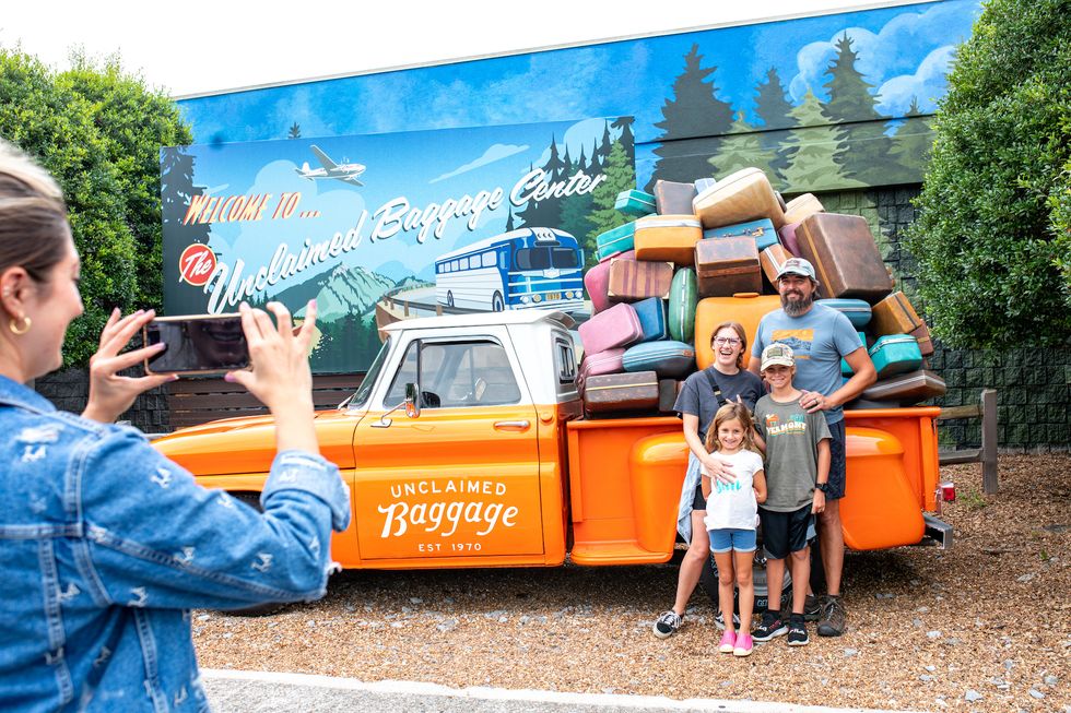 visitors at unclaimed baggage pose in front of a photo backdrop