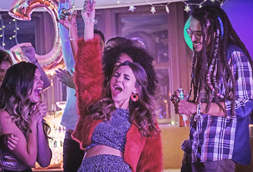 victoria justice, caracterizada como cassie en la película de netflix la fiesta del más allá, alza una copa y grita en una fiesta