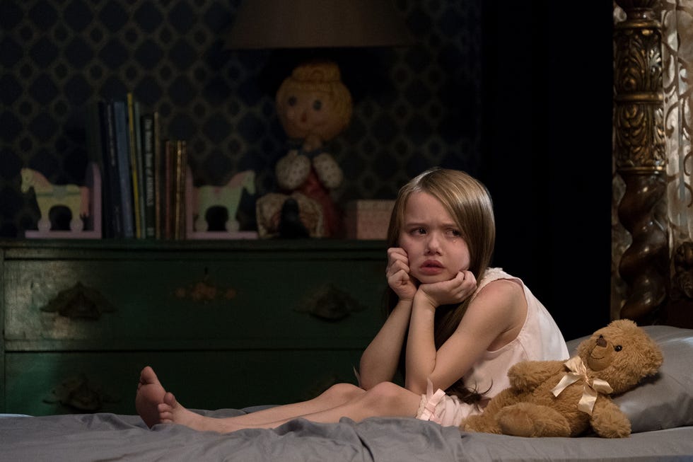 la niña de la maldición de hill house sobre una cama con un osito