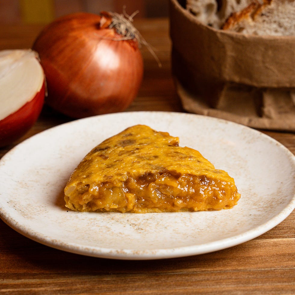 a slice of savory dish on a plate with onions and bread in the background