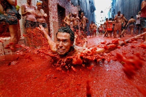 Een man geniet op een glijbaan van vertrapte tomaten tijdens het feest van La Tomatina in het Spaanse Buol
