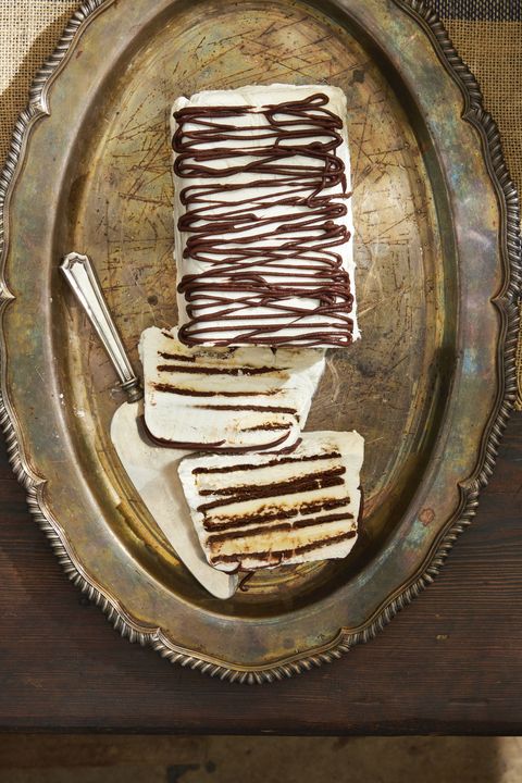 zebra semifreddo covered in whipped cream and drizzled with chocolate on a metal serving tray with a cake server