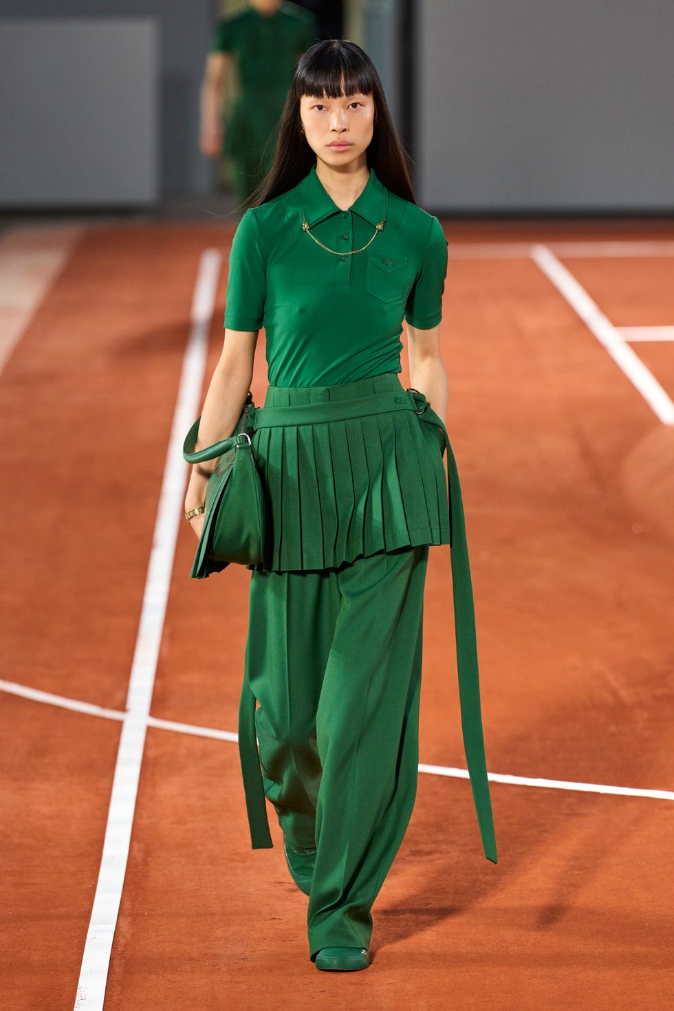 A woman in a green dress holding a tennis racket