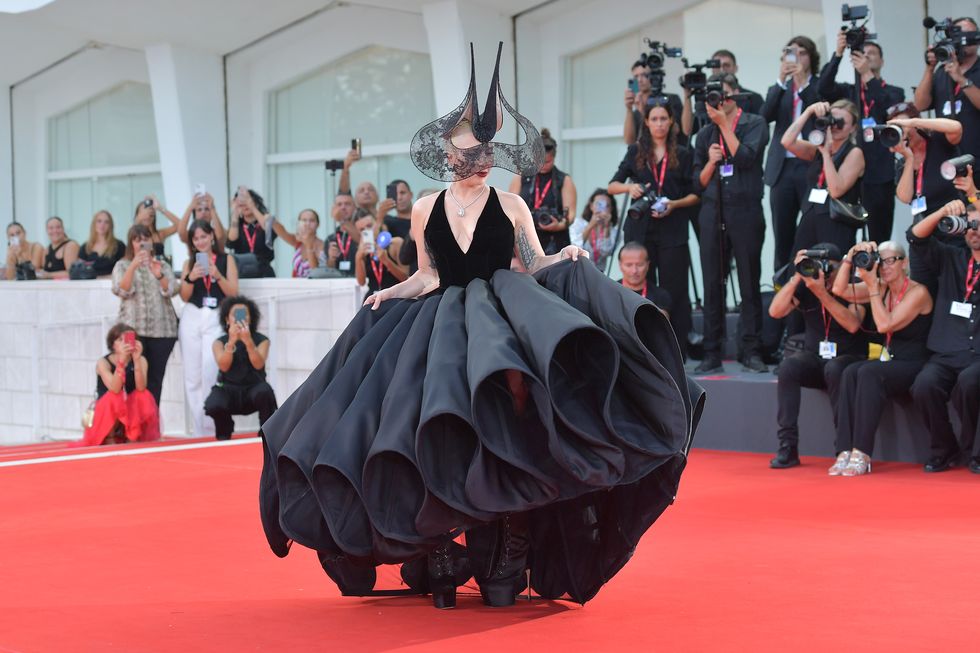 a woman in an elaborate black headpiece and gown on a red carpet