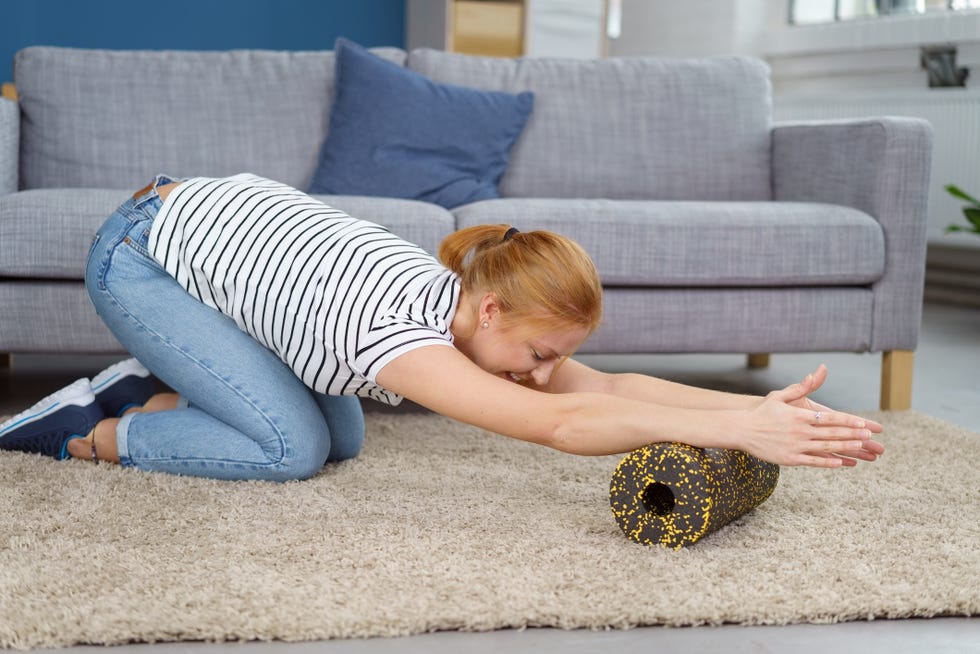 lady massages arms while stretching with foam roll