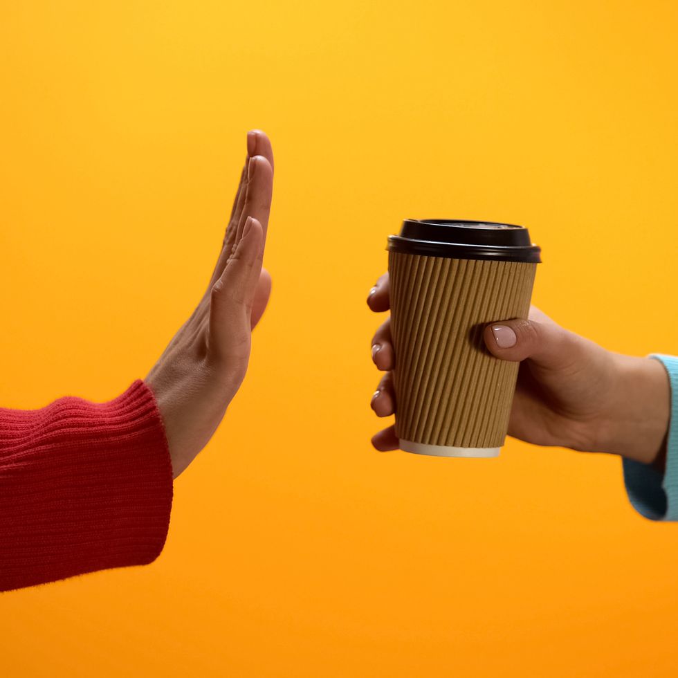 lady showing stop gesture to paper cup on bright background, recycling problem