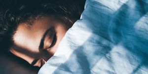 lady sleeps in bed tossing turning in dream under blanket