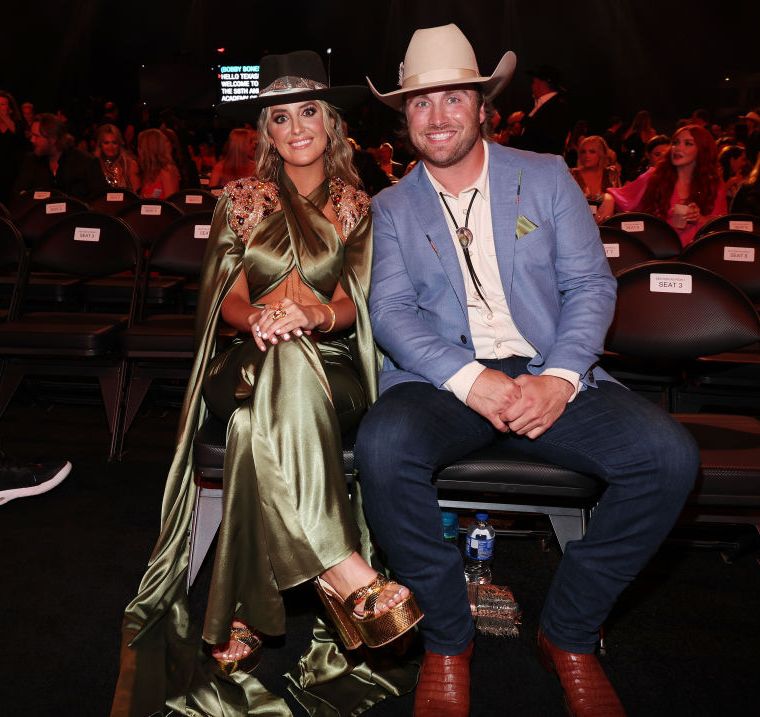 lainey wilson and devlin hodges sitting in their seats for an awards show and smiling for a photo