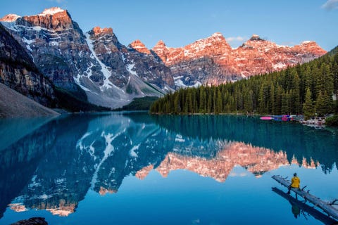 In Alberta Canada wordt het berglandschap weerspiegeld in het spiegelgladde water van het Moraine Lake nabij Banff Ook al is het Moraine Lake een van de drukste bezochte meren van Canada we konden bij zonsopgang toch nog een paar rustige minuten voor onszelf ontdekken zegt fotografe Ana Knezevic De winter of het voorjaar is de beste tijd voor een ochtendwandeling het makkelijk begaanbare anderhalve kilometer lange pad rond het meer is in de zomer en herfst vaak ten dele afgesloten vanwege de hoge activiteit van grizzlyberen