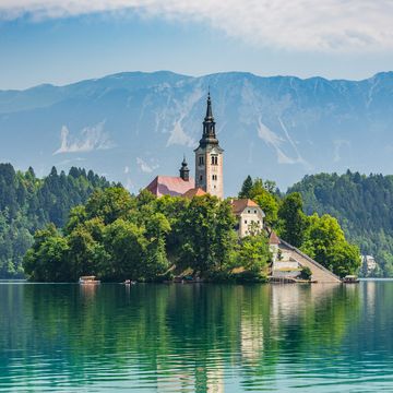 beautiful lake bled in slovenia 'church dedicated to the assumption of mary' santa maria church with surrounding houses and clock tower in the middle of small islet in the famous slovenian lake alps in the background lake bled, slovenia, europe