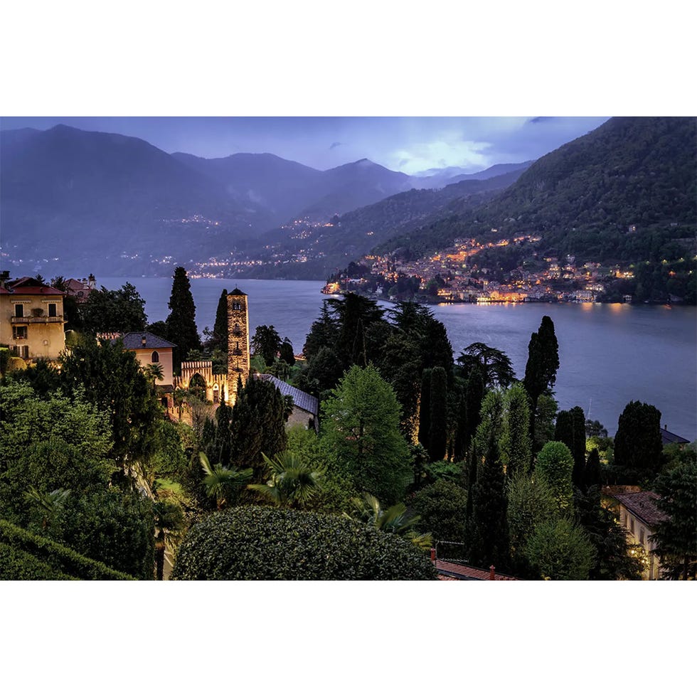 scenic view of a lakeside town at dusk surrounded by mountains