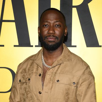 lamorne morris, a man stands with hands in his pockets wearing a brown jumpsuit