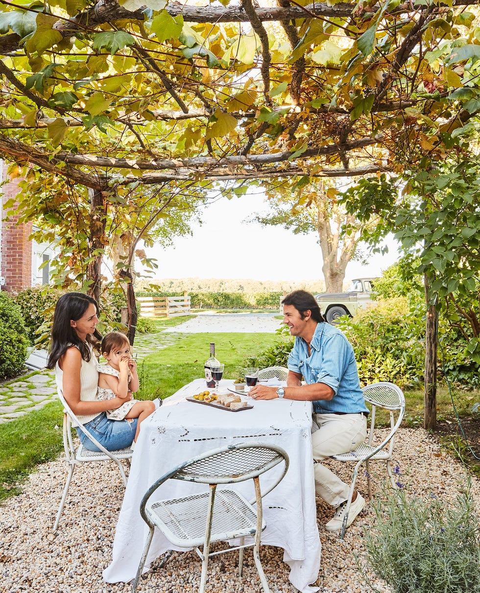 a man and woman sitting at a table outside under a pergola