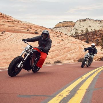 two people riding motorcycles on a road