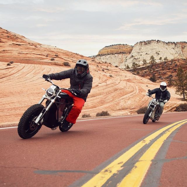 two people riding motorcycles on a road