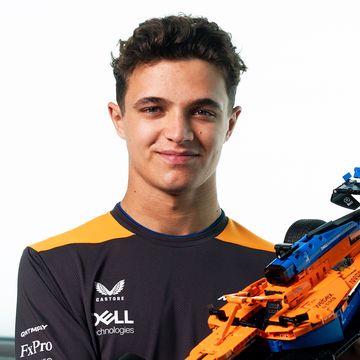 formula 1 driver lando norris smiles as he holds the lego technic mclaren f1 car, product id number lego 42141