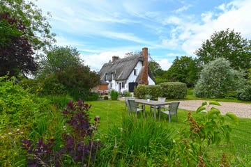 thatched cottage with a bench in a garden