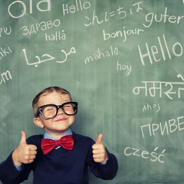 een jongetje staat voor een schoolboord met het woord hallo in verschillende talen