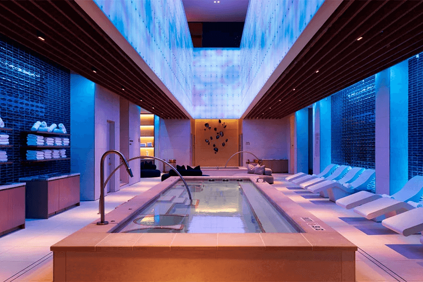 luxury spa area with a hot tub and loungers under blue lighting luxury spa area with a hot tub and loungers under blue lighting