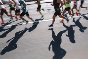 large group of people running fast in the city, defocused light and shadows sports background