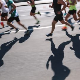 large group of people running fast in the city, defocused light and shadows sports background