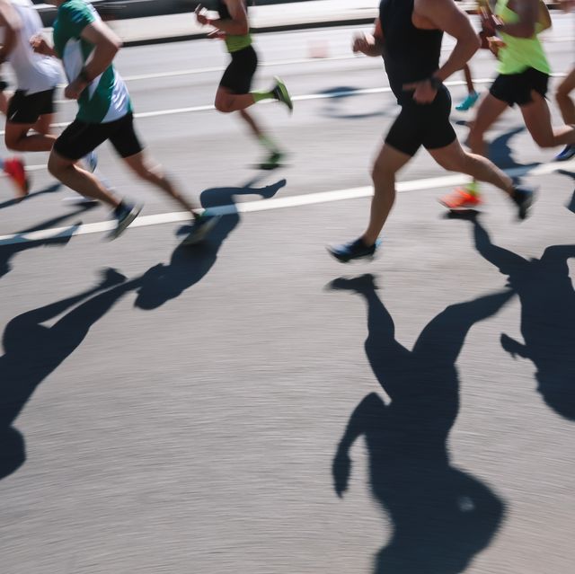 large group of people running fast in the city, defocused light and shadows sports background