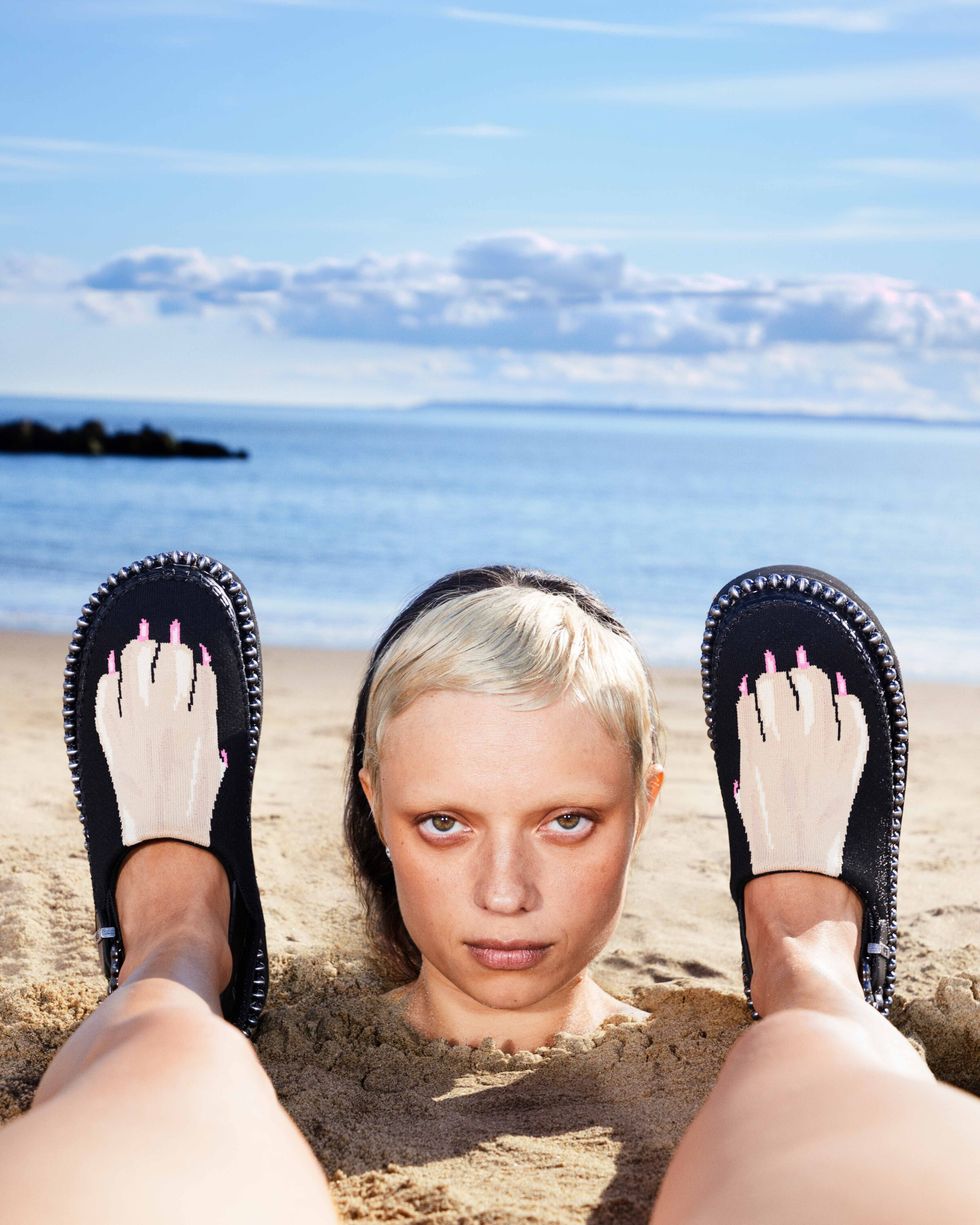 a person holding flip flops on a beach