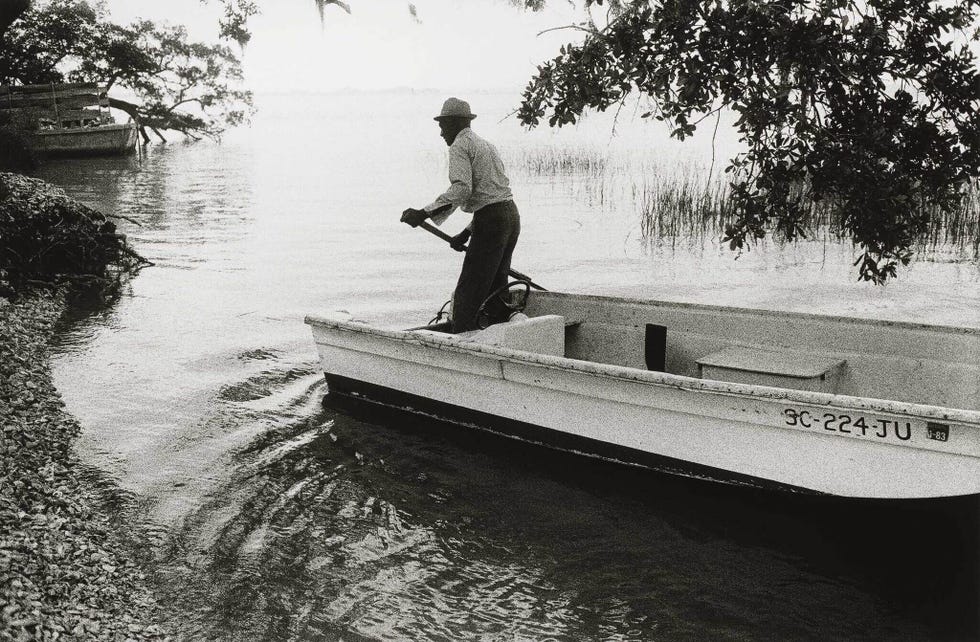 man operating a small boat in a calm waterway