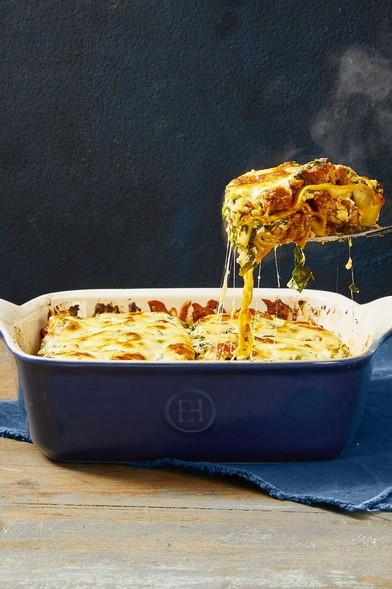 lasagna with meat sauce in a blue ceramic casserole dish