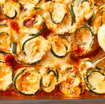 zucchini slices rolled up around cheese with sauce in a casserole dish