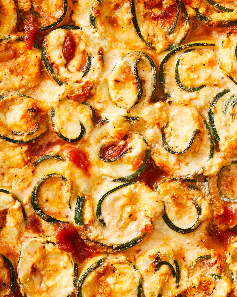 zucchini slices rolled up around cheese with sauce in a casserole dish