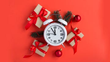 top view of white alarm clock and christmas composition on the red background close up
