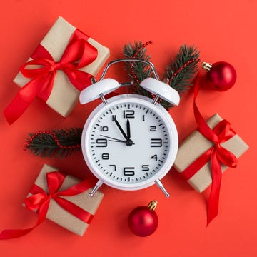 Last Minute Christmas top view of white alarm clock and christmas composition on the red background close up