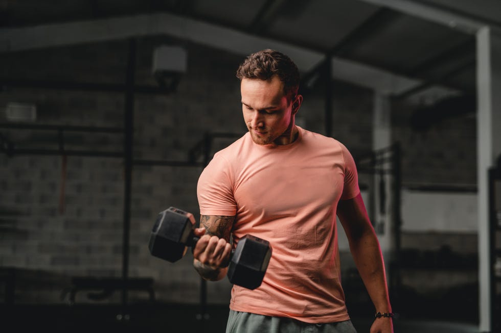 late 20s male athlete working out with dumbbell