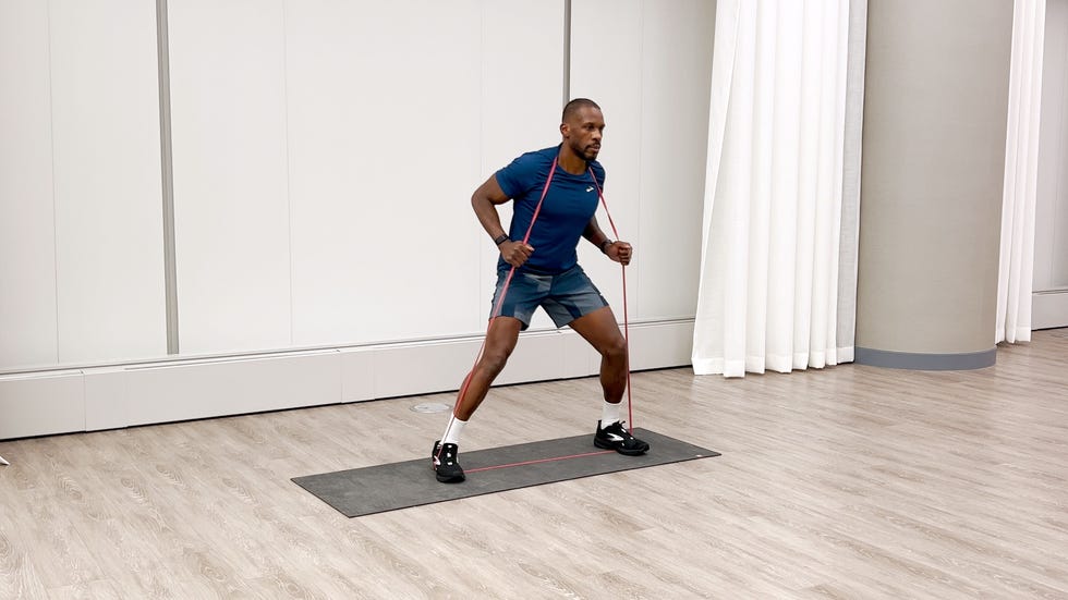 man performing lateral walk with a resistance band on an exercise mat in a gymlike enviroment.
