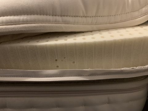 an original photograph of a latex mattress partially unzipped to showcase the latex foam in the pillow top layer
