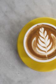 latte art in a yellow cup on a marble table