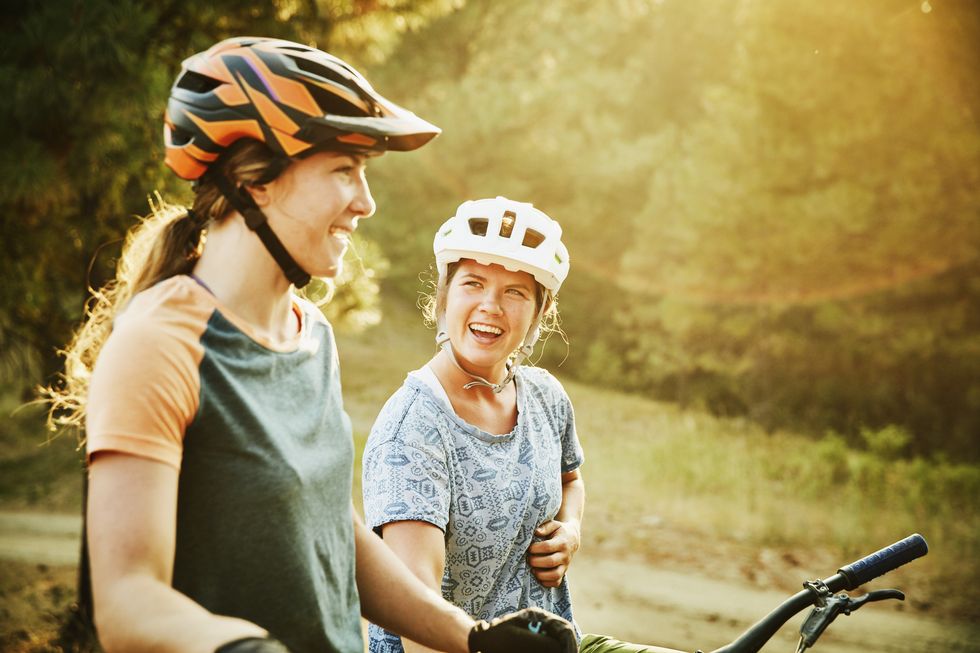 Laughing female mountain bikers in discussion while resting during ride