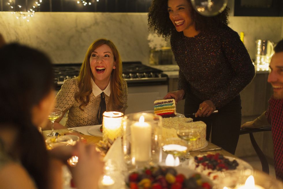 laughing friends enjoying cake at candlelight christmas dinner party