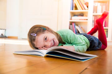 niña riendo mientras lee un libro