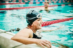 laughing mature swimmer resting between sets of early morning workout in outdoor pool