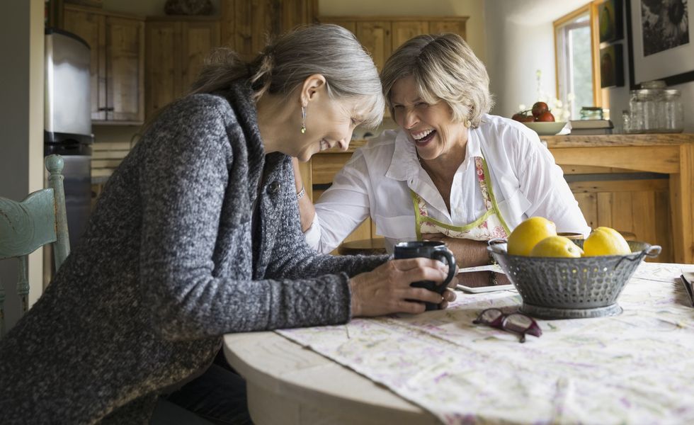 Laughing senior women drinking coffee at dining table